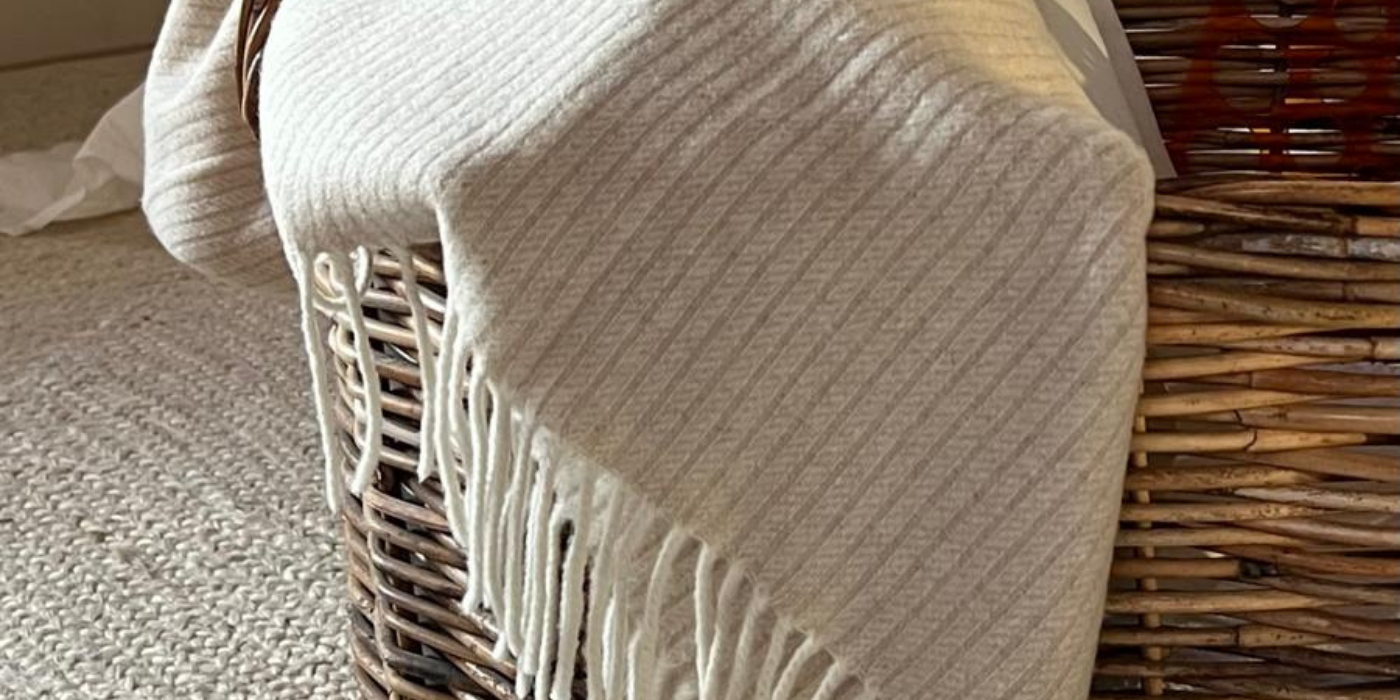 blanket in rattan basket on white jute rug