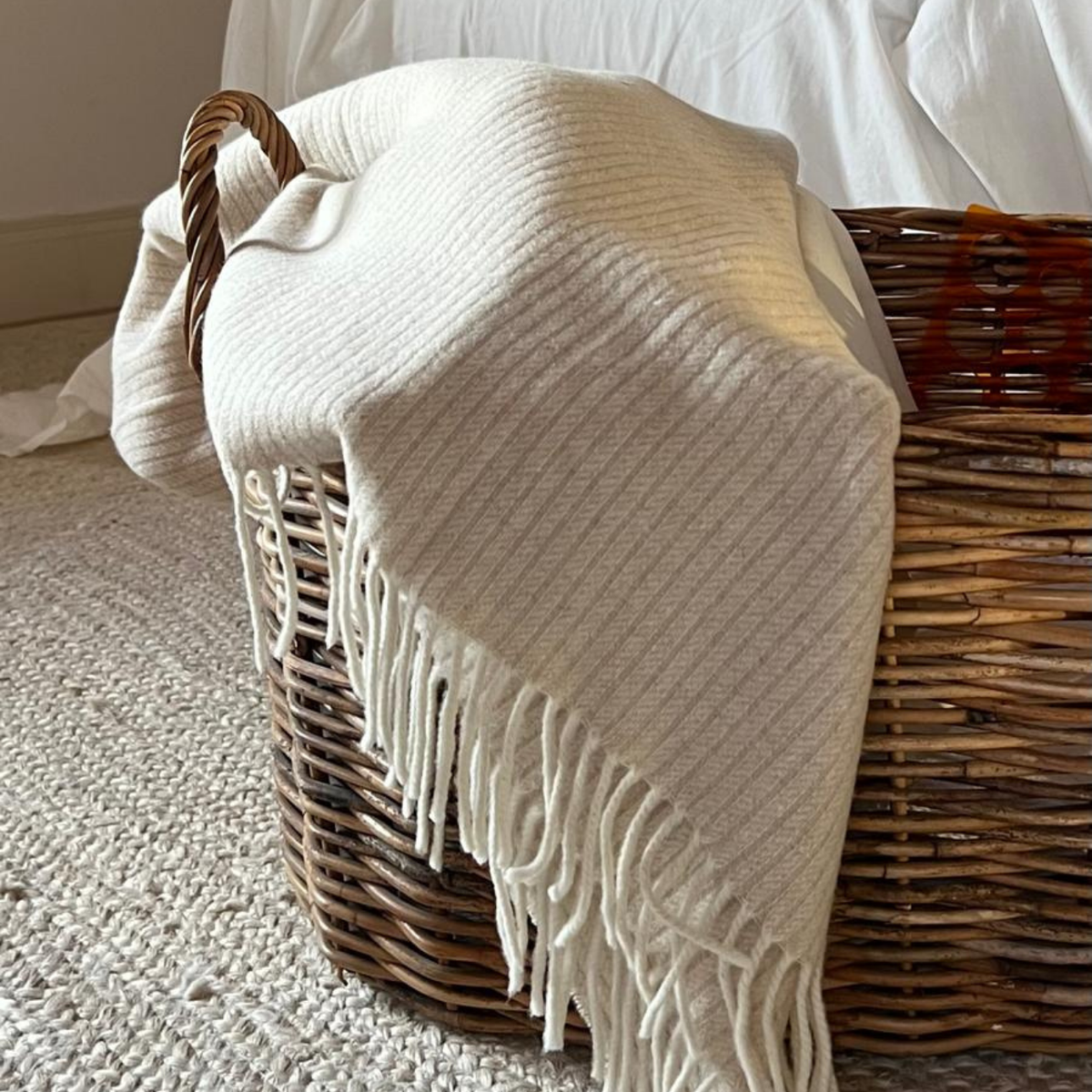 blanket in rattan basket on white jute rug