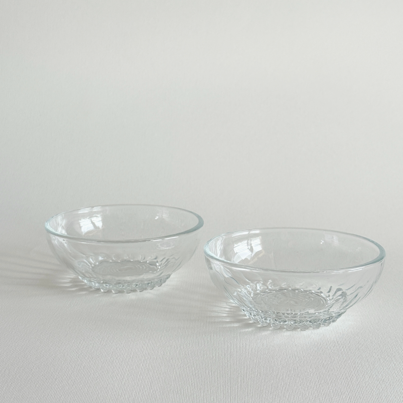 Set of 2 clear pressed glass bowls with bubble feet and round rims, mid-20th century French Reims design