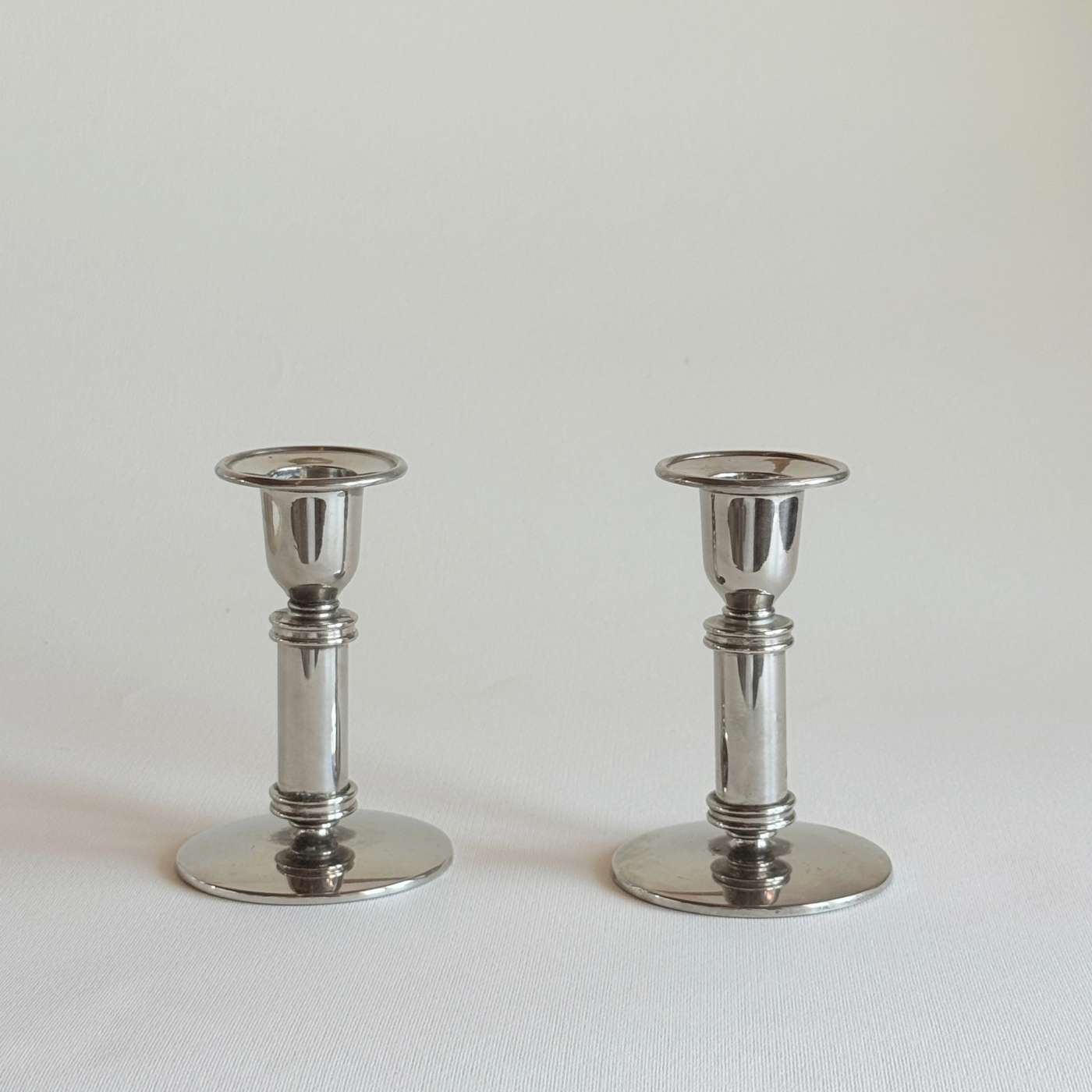 Polished stainless steel candle holder detail, steel column and flat round base, L'Officina General Store