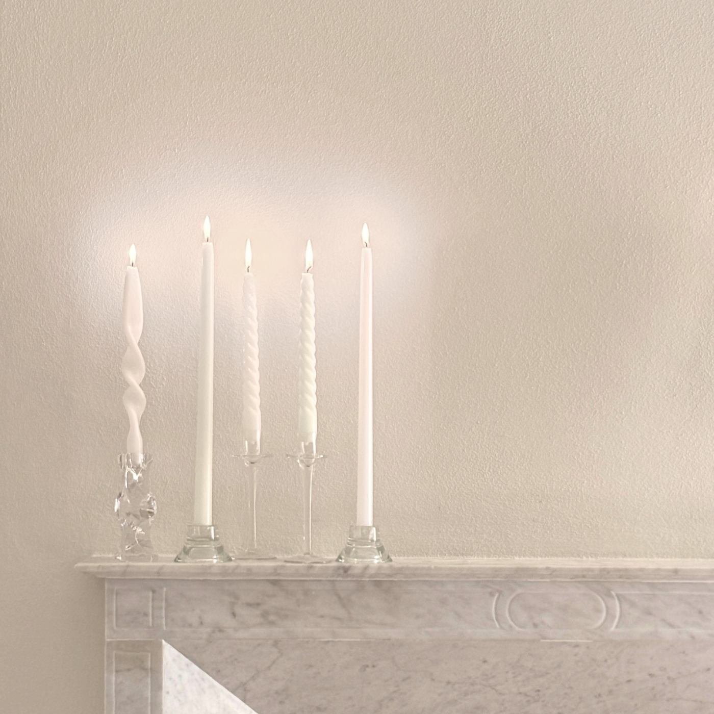 Cereria Graziani Tapered Candles, white wax with smooth and twisted forms, displayed in clear glass holders.