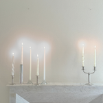 Letang Remy two-arm candle holder in polished stainless steel, with a slender central stem and curved arms holding candles.