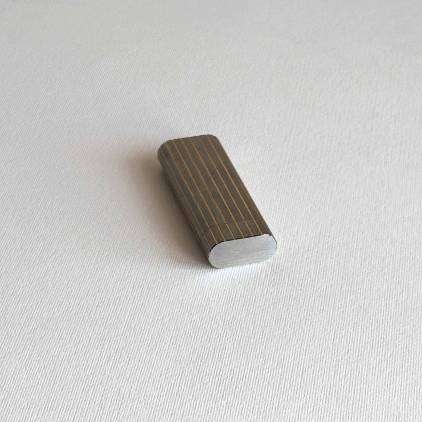 Gold-plated stripe detail on a silver stainless steel Les Must de Cartier table lighter, close view