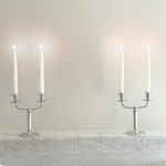 Letang Remy two-arm candle holder in polished silver-tone stainless steel, with a slender stem and curved candle arms.