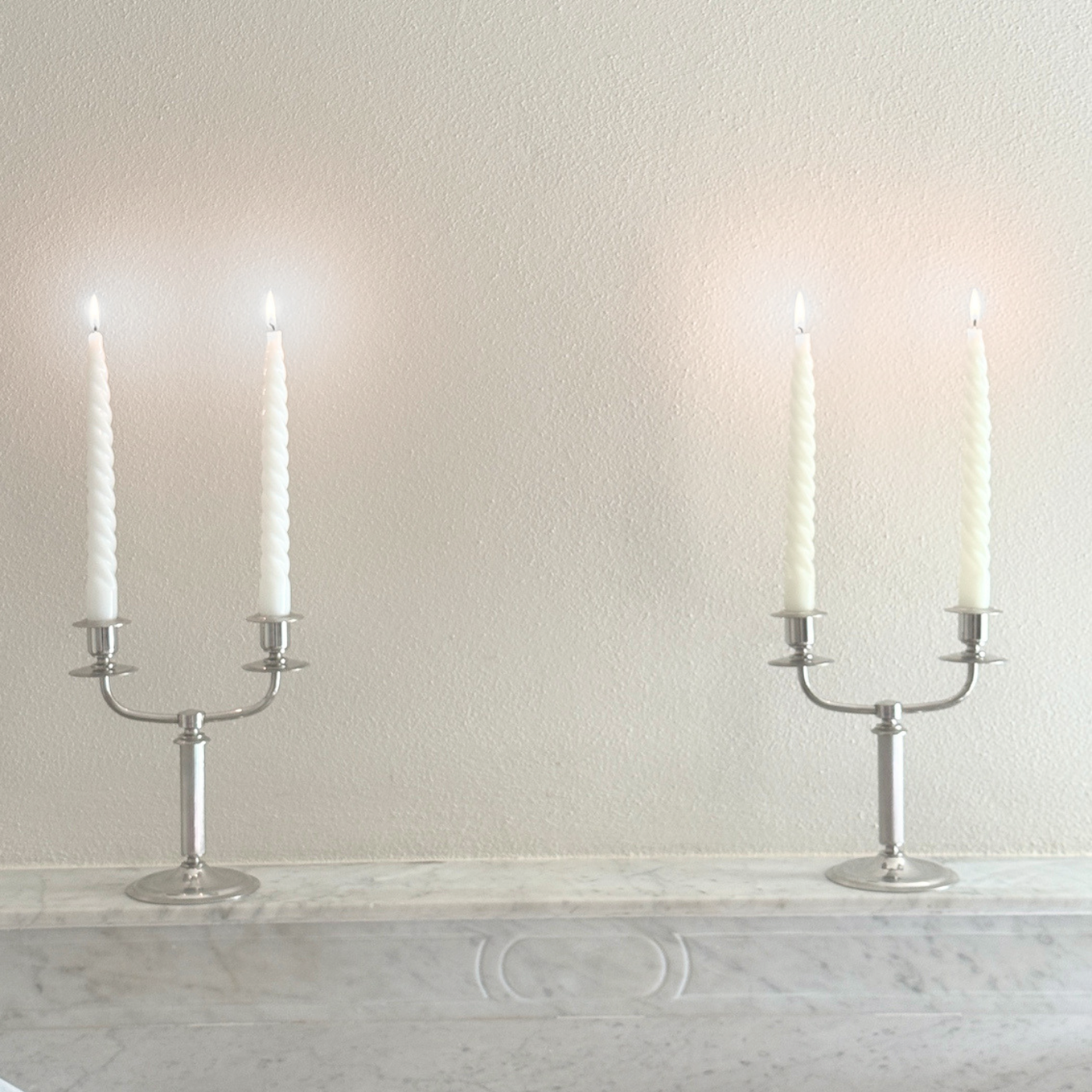Letang Remy two-arm candle holder in polished silver-tone stainless steel, with a slender stem and curved candle arms.
