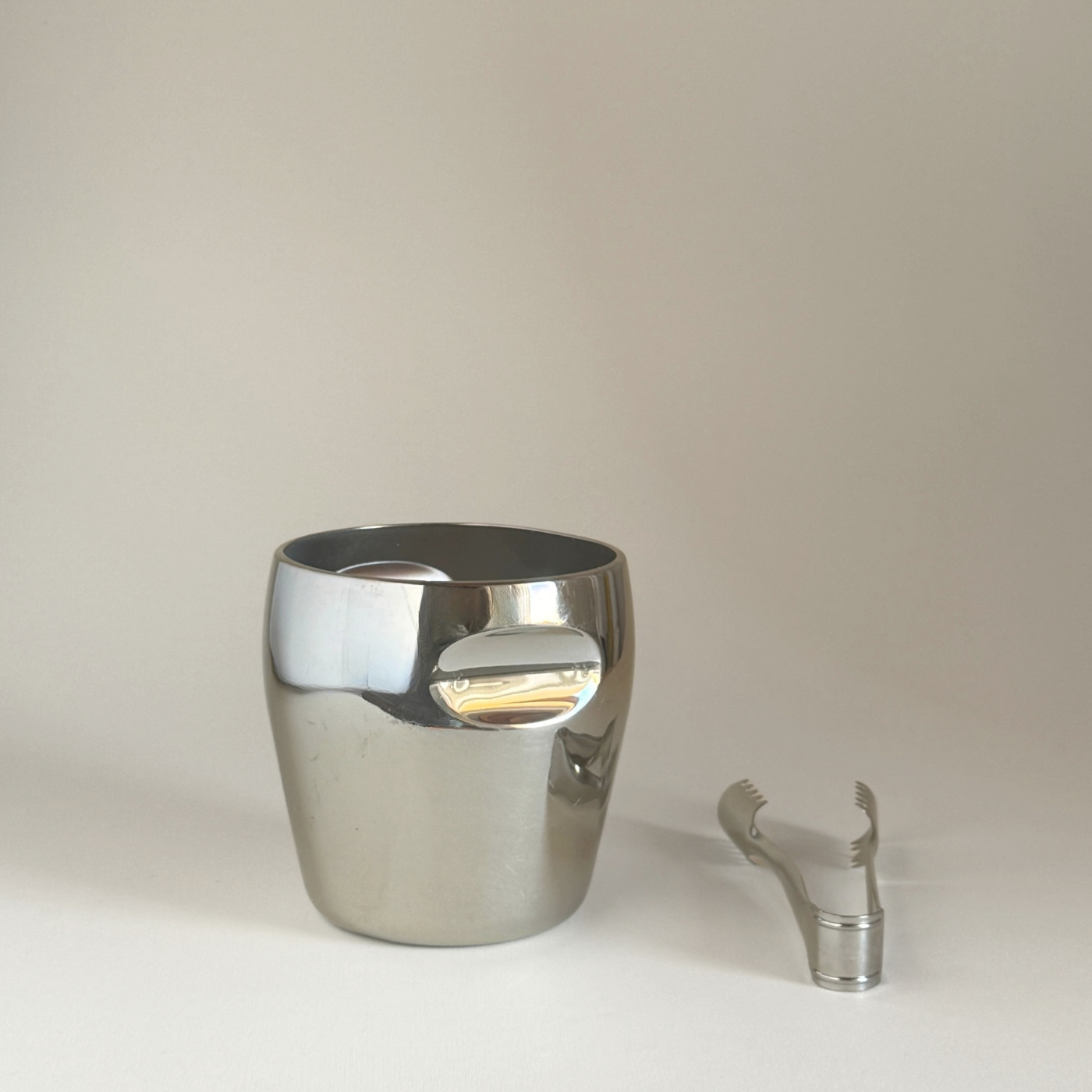 Alessi 871 Ice Bucket in mirror-polished stainless steel with a cylindrical form and matching stainless steel ice tongs.