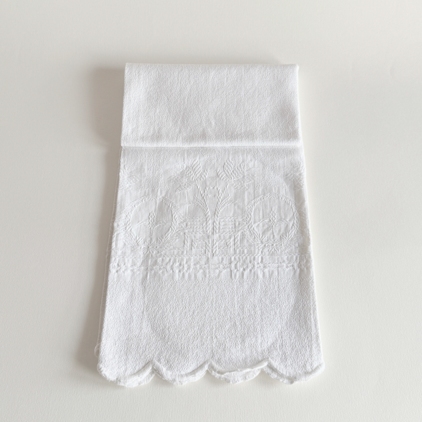 Antique white cotton hand towel with floral and fleur-de-lys jacquard, laid flat