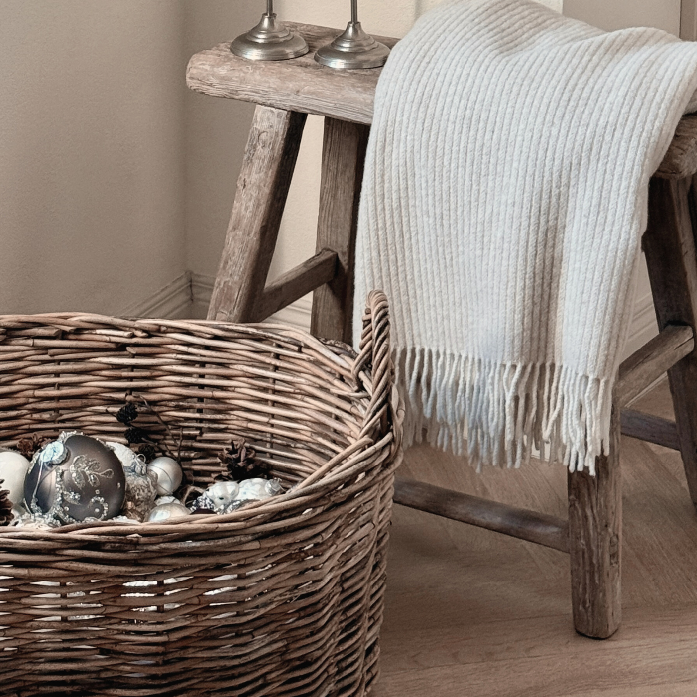 Beige Sustainable Wool and Cashmere Throw made in Italy from recycled cashmereon stool with rattan basket