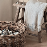 Beige Sustainable Wool and Cashmere Throw made in Italy from recycled cashmereon stool with rattan basket