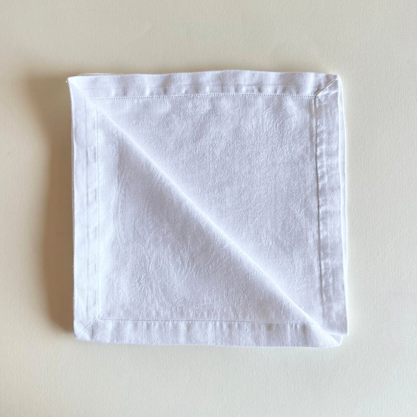 White jacquard cotton napkin folded on a beige background