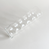 Ribbed ripple glass vase styled with a single stem on a console