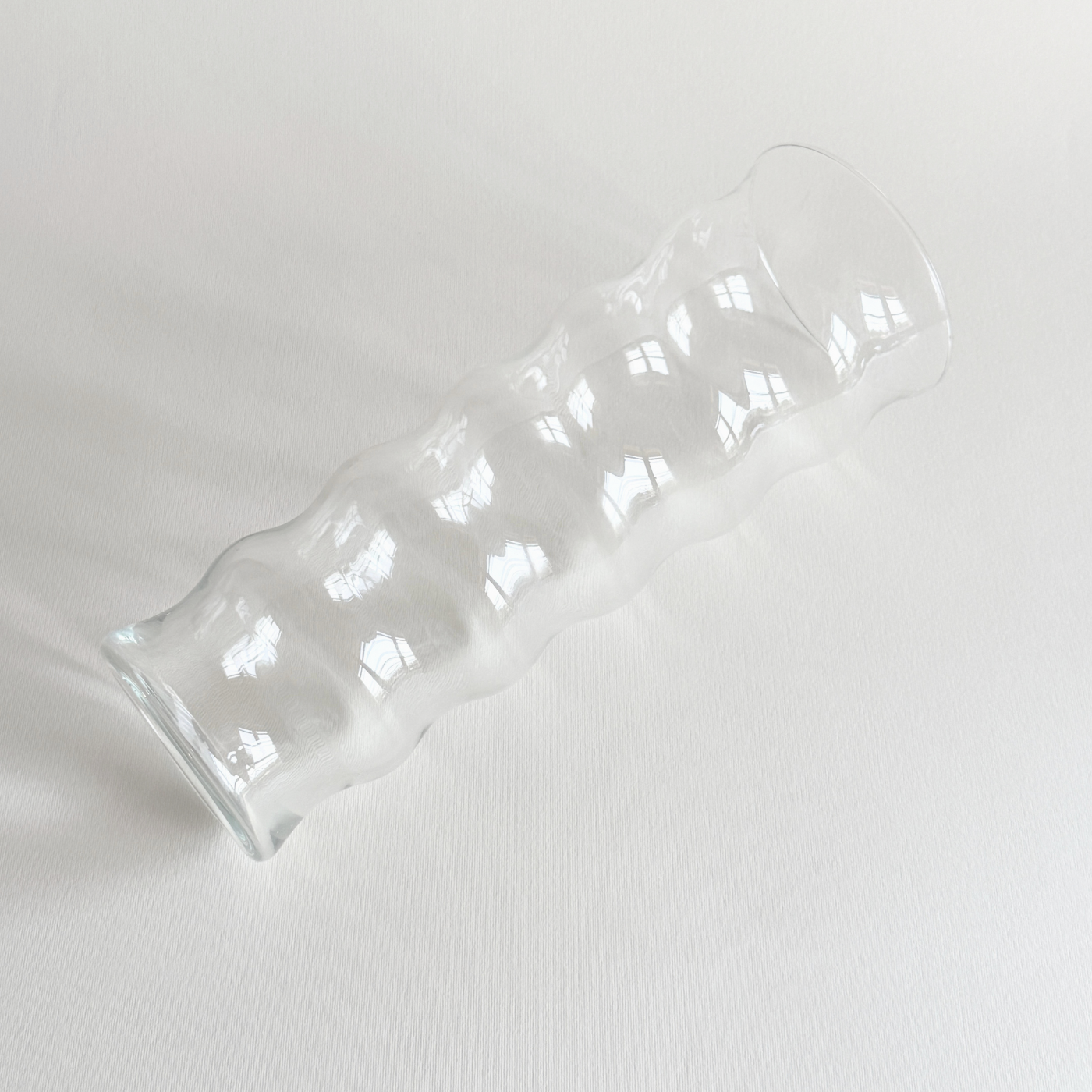 Ribbed ripple glass vase styled with a single stem on a console