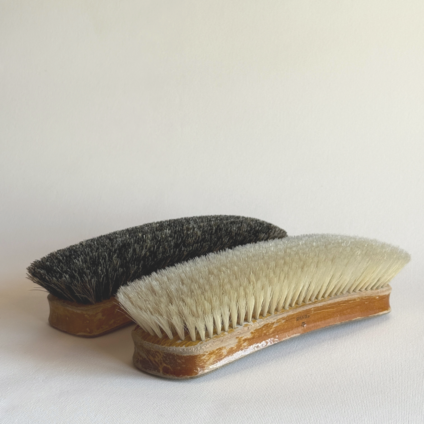 Two bristle brushes with wooden handles on a light background