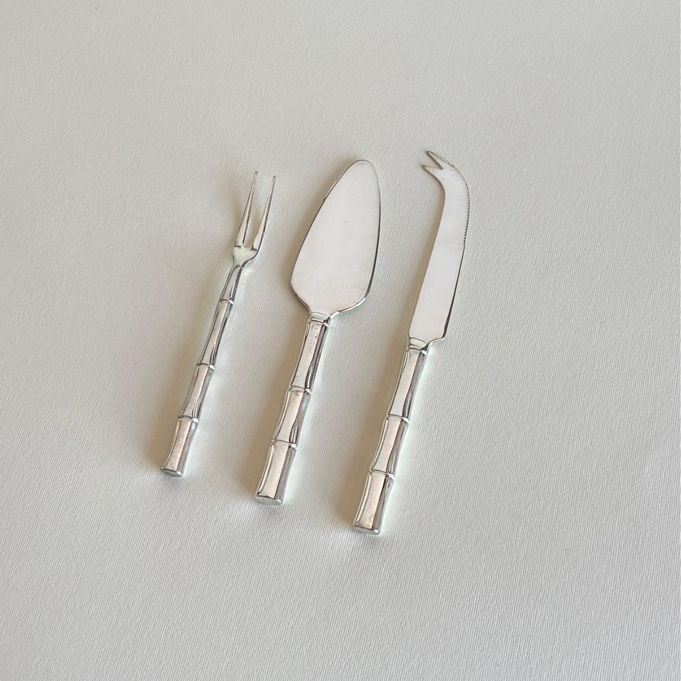 Silver-plated cheese server blade close-up, bamboo-motif silver cutlery set of three, made in Italy