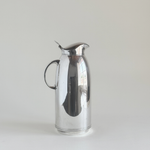 Silver plated thermos jug — front three-quarter view showing mirror-polished body, circular loop handle and hinged flip-top lid, Italian 1970s
