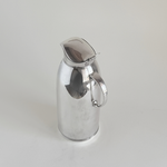 Silver plated thermos jug — close-up of mirror-polished body showing micro-scratches consistent with regular use