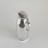Silver plated thermos jug — close-up of mirror-polished body showing micro-scratches consistent with regular use