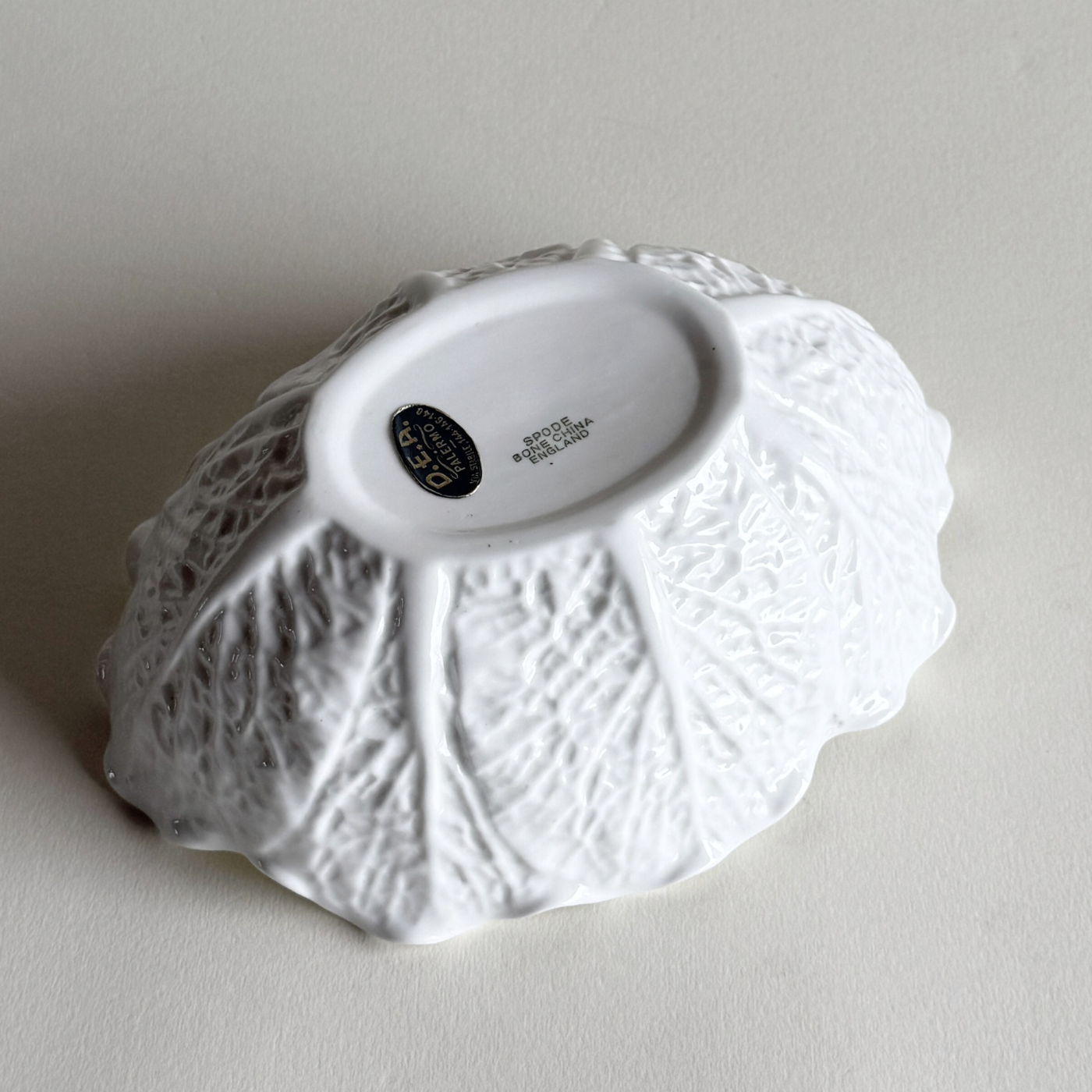 White ceramic savoy cabbage bowl with textured surface on a light gray background