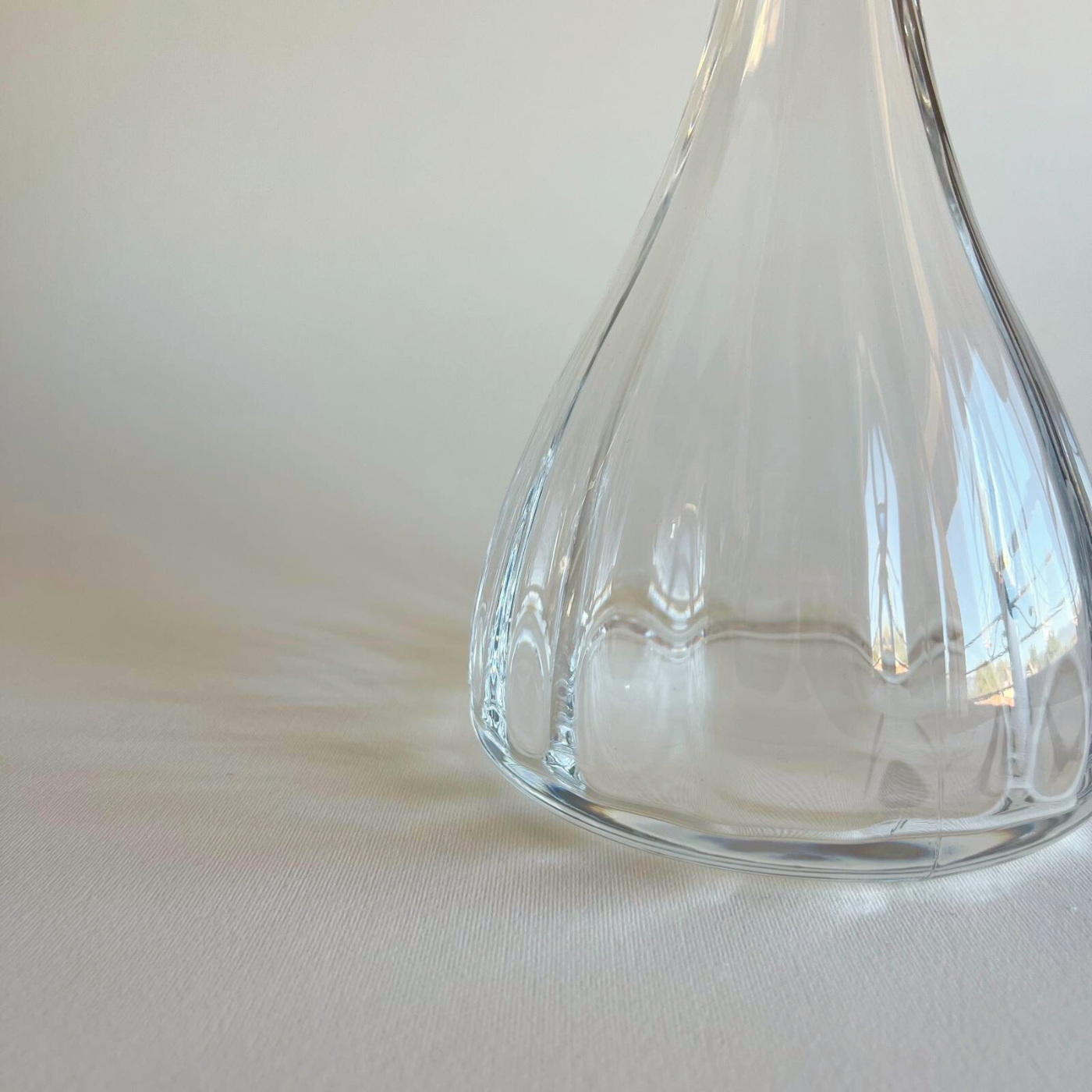 Clear glass decanter with a spherical stopper on a light beige background