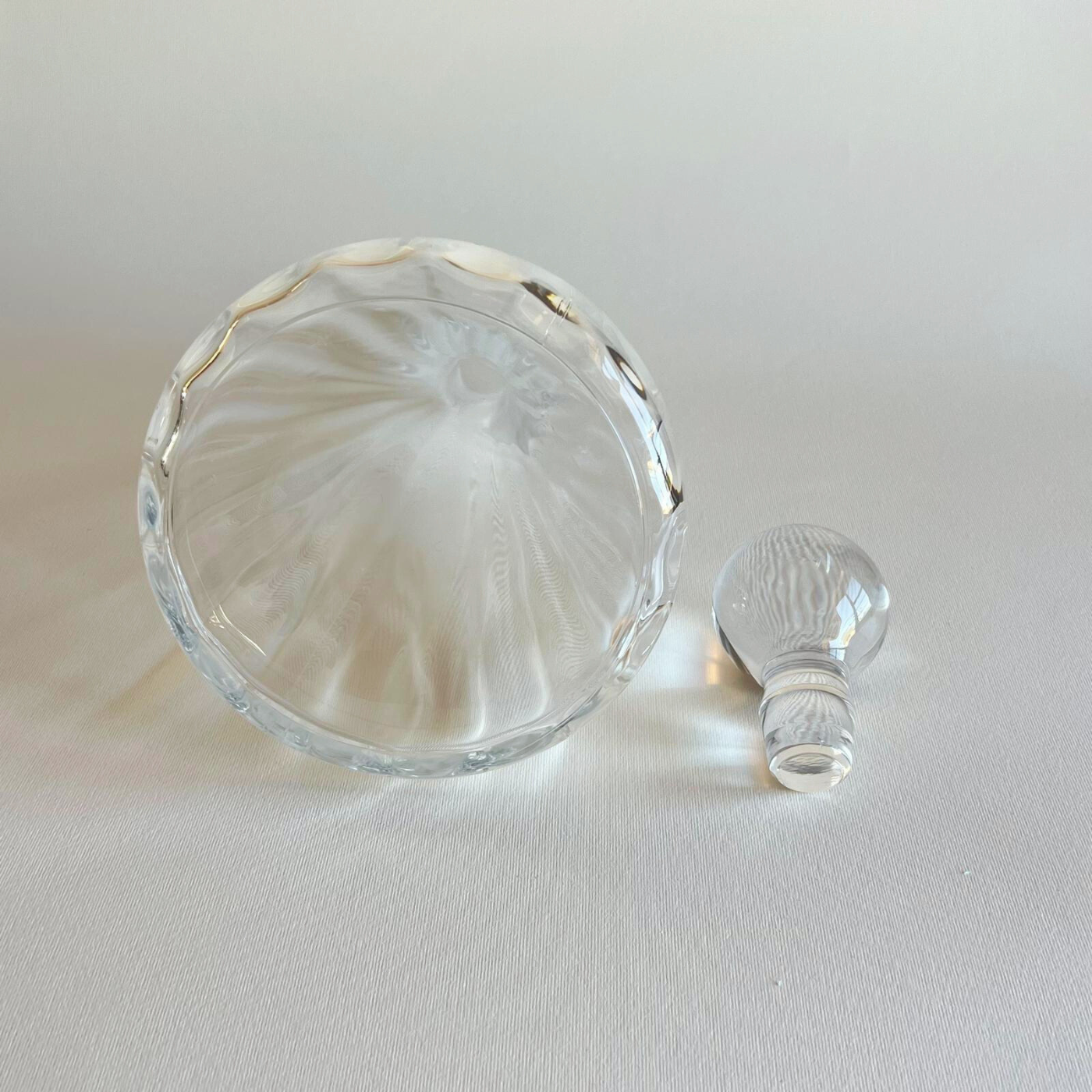 Clear glass decanter with a spherical stopper on a light beige background
