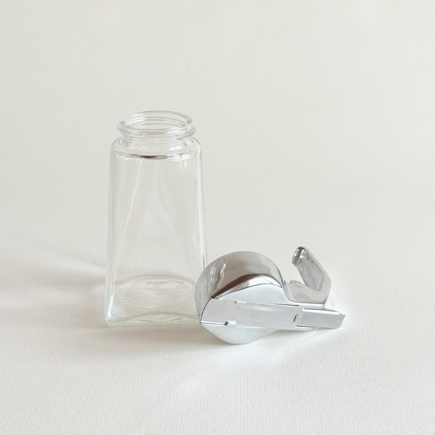 Square-based glass sugar dispenser with its stainless lid removed