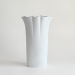 White ceramic vase — three-quarter view showing fluted columns running full height of body