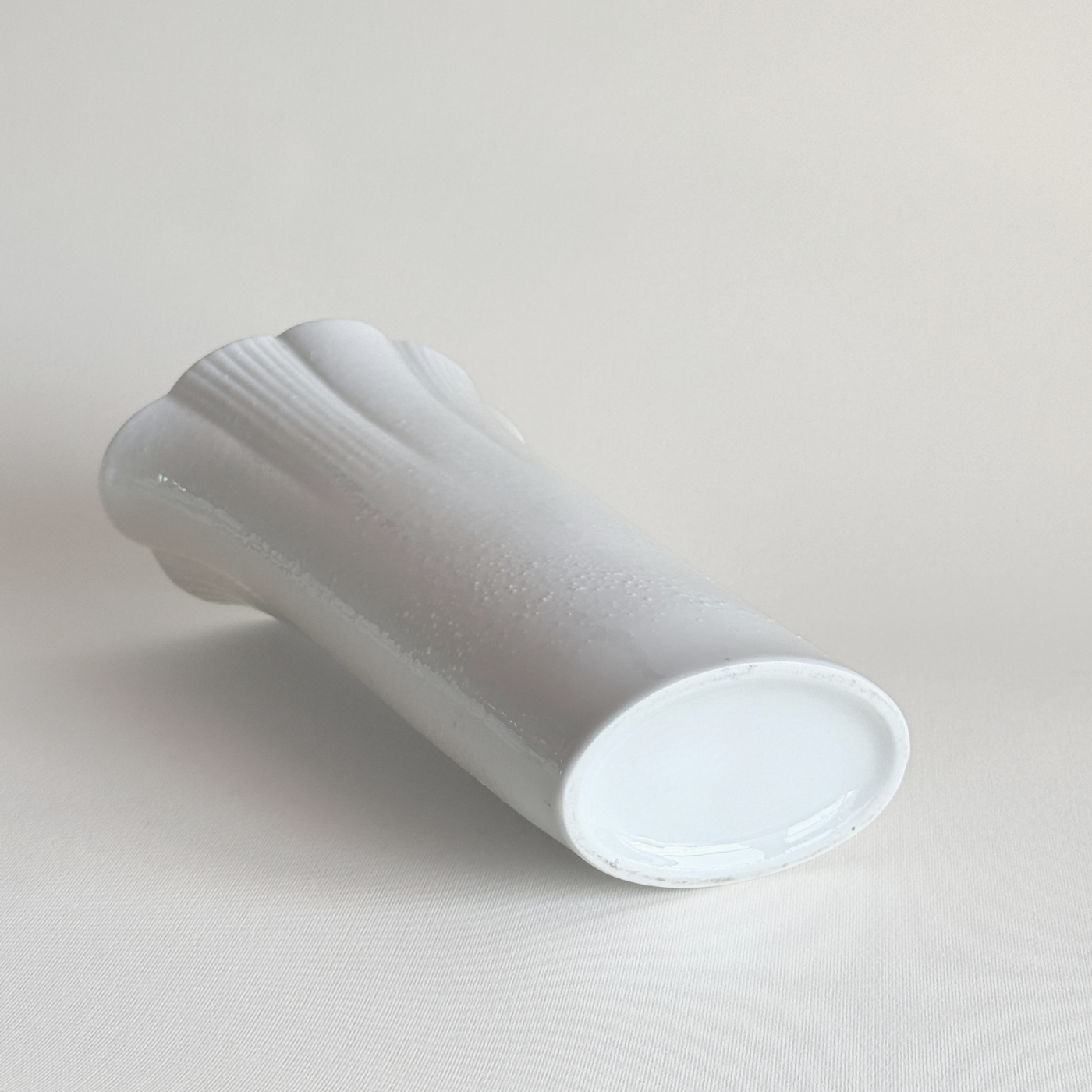 White ceramic vase — close-up of scalloped rim showing wave edge detail and white glaze