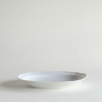 Rectangular white porcelain plate at an angle, smooth even glaze