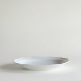 Rectangular white porcelain plate at an angle, smooth even glaze