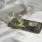 Breakfast set for one with stainless steel tray, pressed glass espresso cup, and ramekin on wooden table