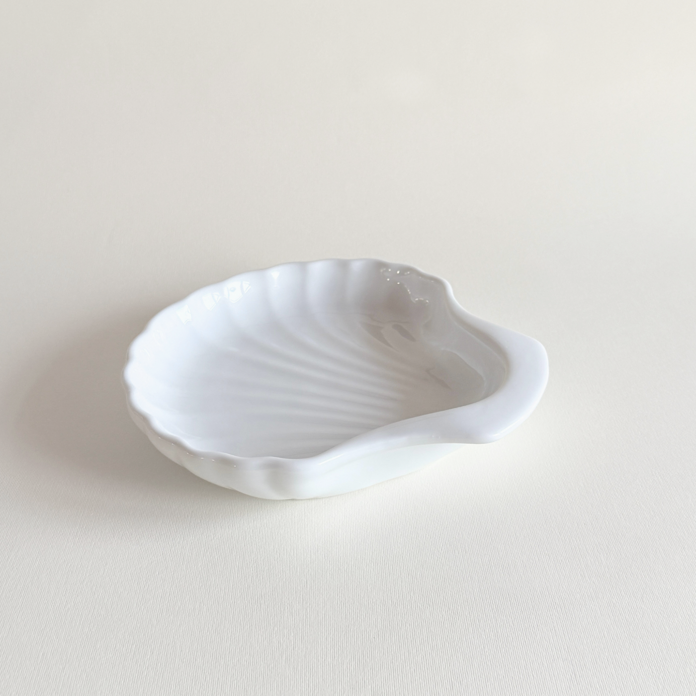 White porcelain shell dish in profile, deep enough for roasting