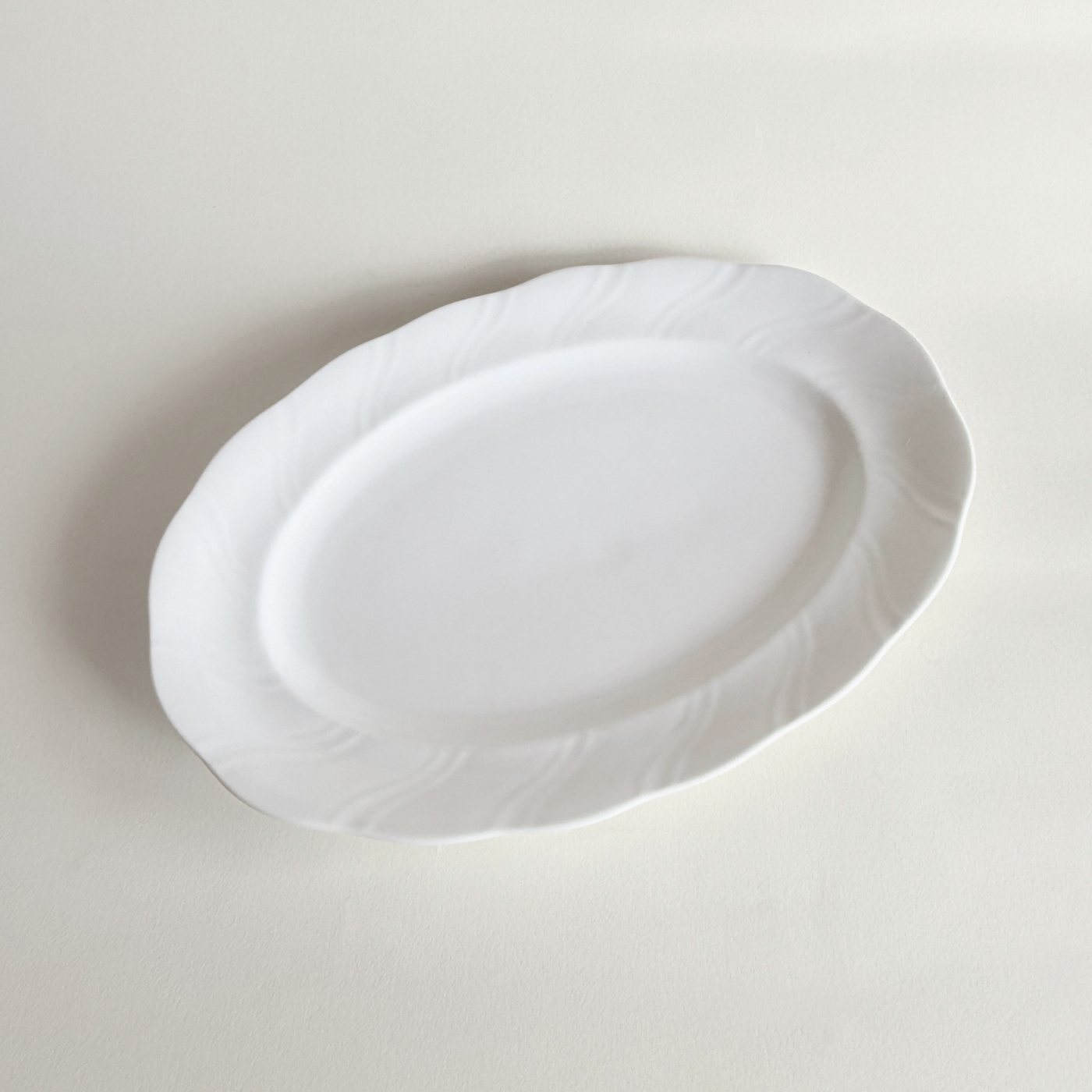 White oval porcelain serving dish — full top view, 33.5 × 23 cm, swirl relief detail across surface