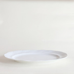 Close-up of swirl relief detail on white porcelain oval serving dish — even glaze, no crazing
