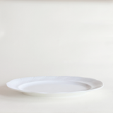 Close-up of swirl relief detail on white porcelain oval serving dish — even glaze, no crazing