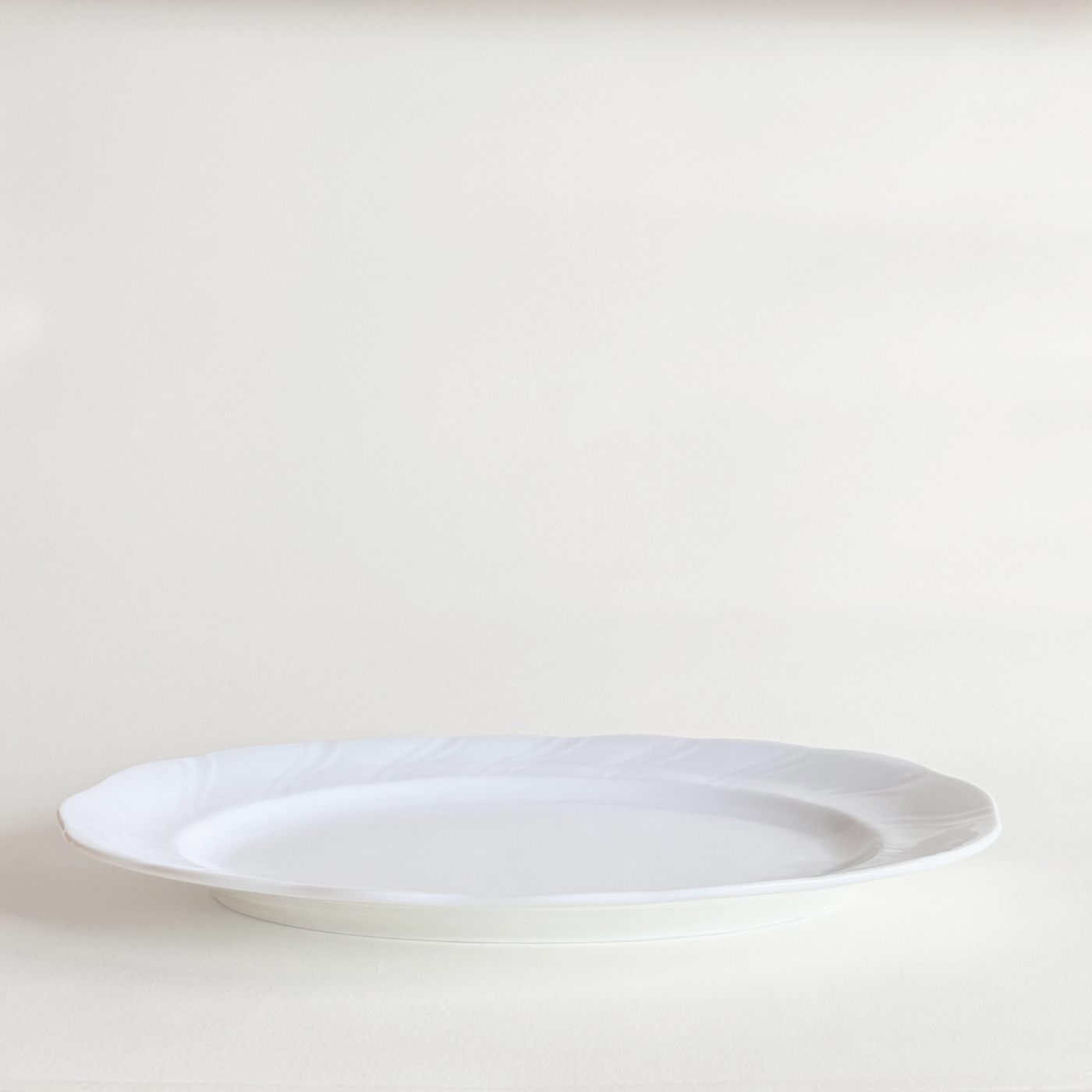Close-up of swirl relief detail on white porcelain oval serving dish — even glaze, no crazing